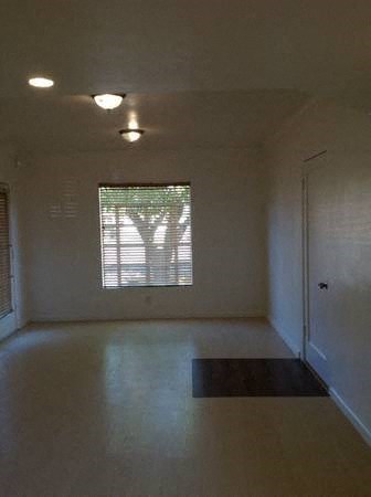 an empty living room with a door and a window