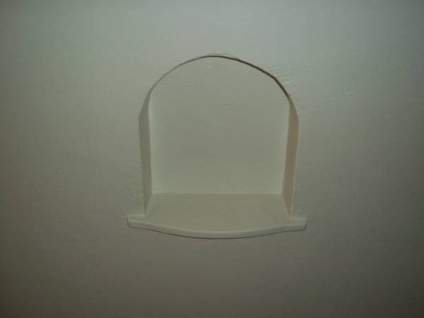 a white wall with a white shelf on it