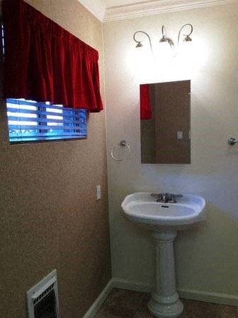 a bathroom with a sink and a mirror and a red curtain