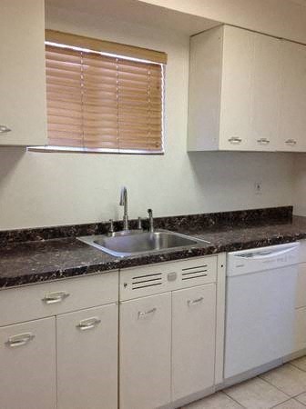 a kitchen with white cabinets and a sink and a window