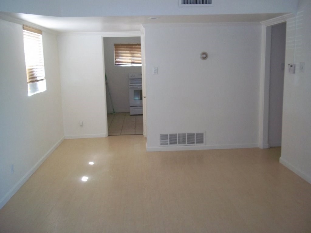 an empty living room with an open door to a kitchen