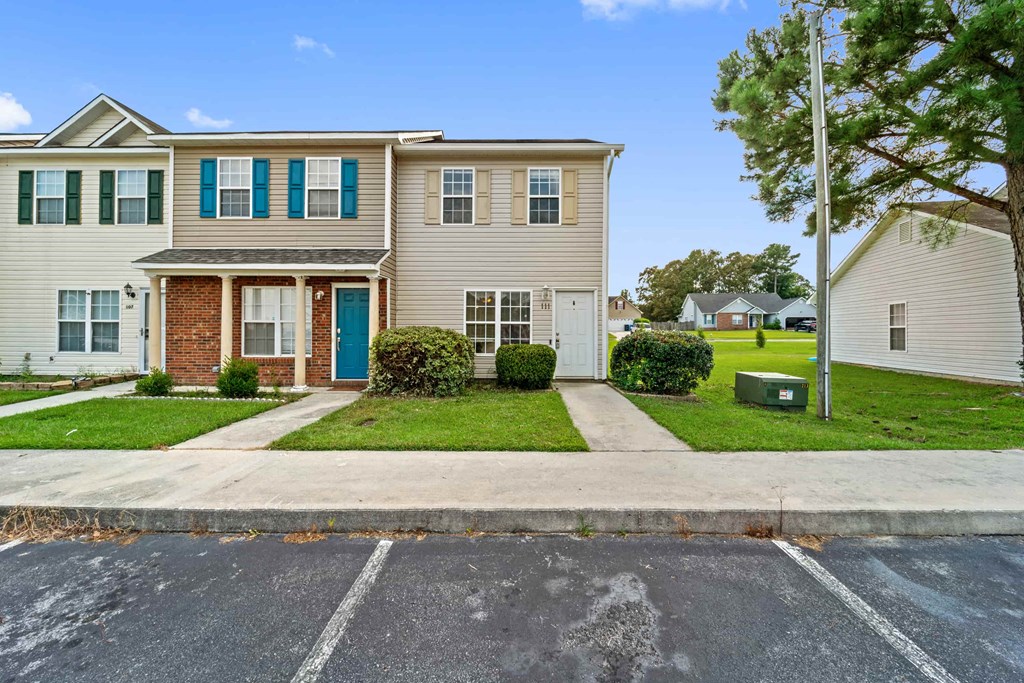 a white house with blue shutters and a sidewalk in front