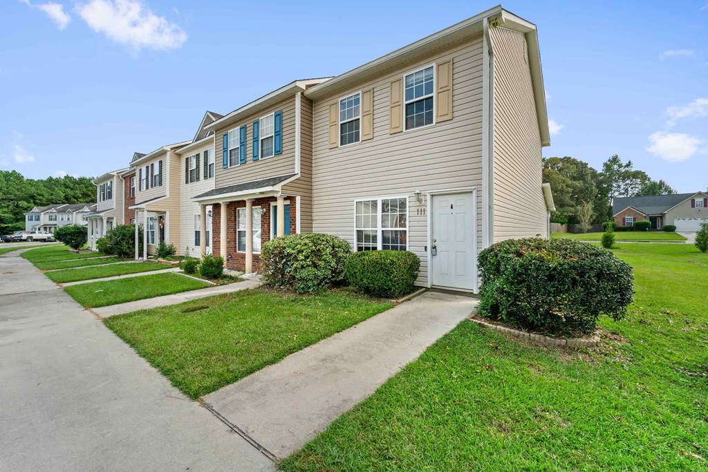 a row of town homes with sidewalks and green lawns
