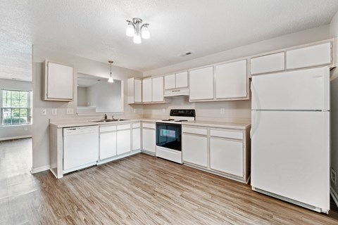 an open kitchen with white cabinets and appliances and a wooden floor