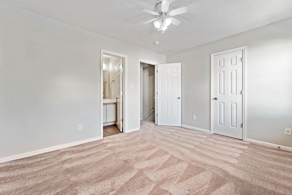 an empty living room with carpet and a ceiling fan