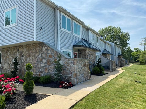 a white house with a stone wall and blue siding
