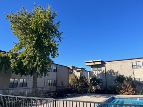 an apartment building with a swimming pool and a tree