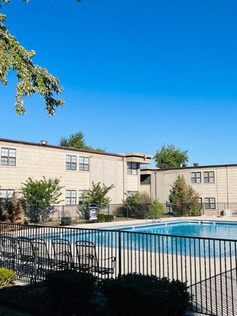 a swimming pool with chairs in front of an apartment building