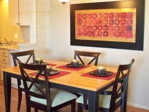 a dining room table with chairs and a painting on the wall