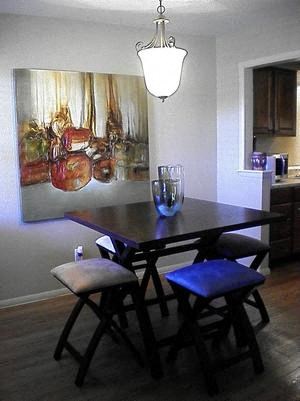 a dining room table with three stools and a painting