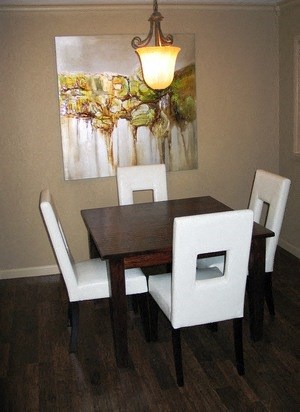 a dining room table with white chairs and a painting on the wall