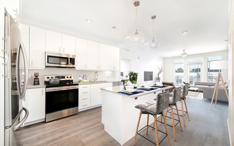 a kitchen with white cabinets and a bar with chairs