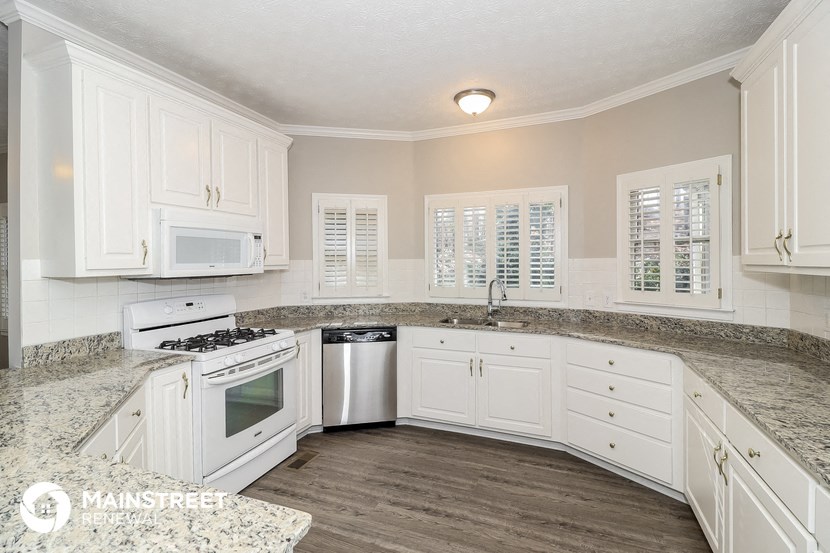 a kitchen with white cabinets and marble counter tops