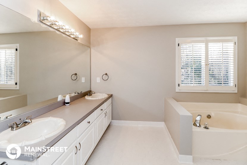 a bathroom with two sinks and a tub and a large mirror