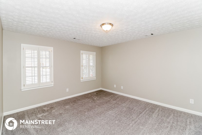 the spacious living room with carpeting and windows