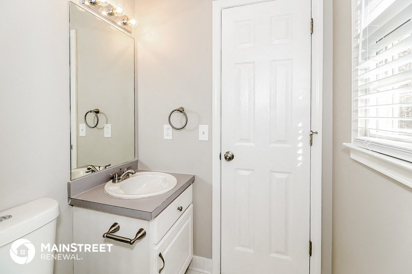a bathroom with a white door and a sink and a mirror