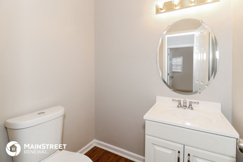 a white bathroom with a white toilet and a sink and a mirror