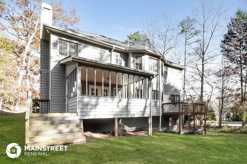 the back of a gray house with a porch and a deck