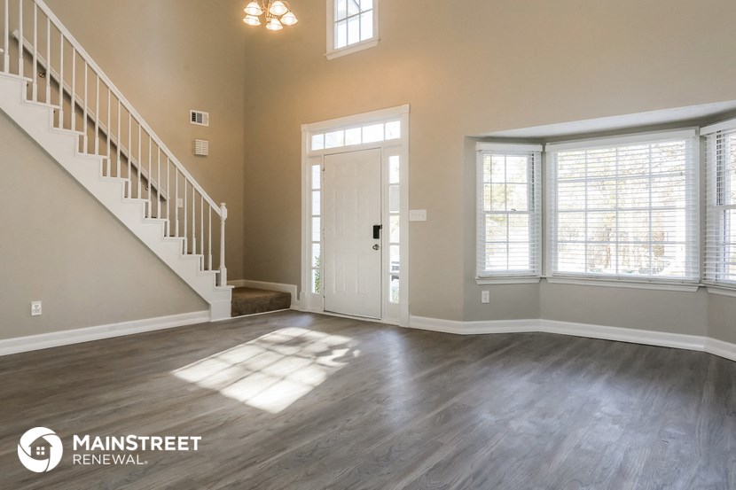 an empty living room with a staircase and a door