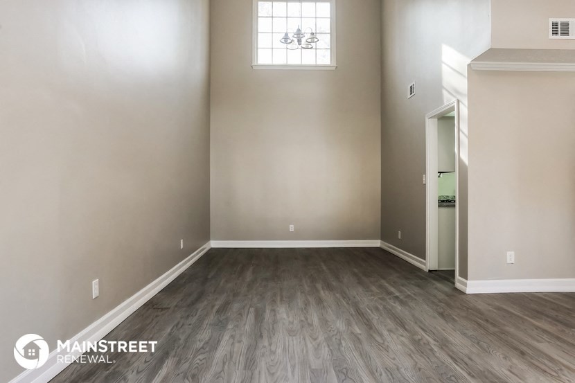 an empty living room with wood flooring and a window
