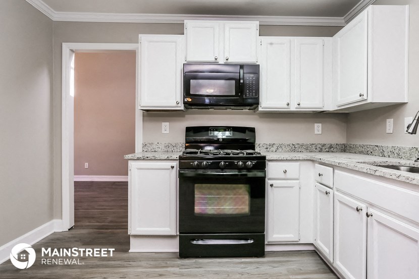 a white kitchen with black appliances and white cabinets