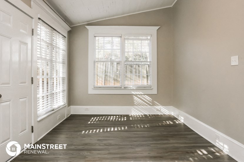 the living room of a home with white walls and a window