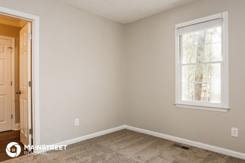 the bedroom of a home with a carpeted floor and a window