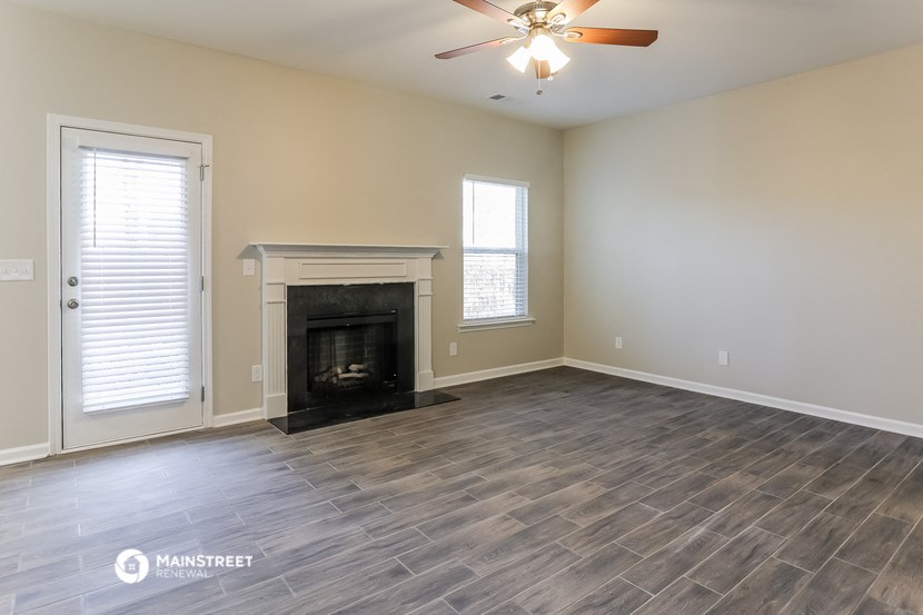 an empty living room with a fireplace and a ceiling fan