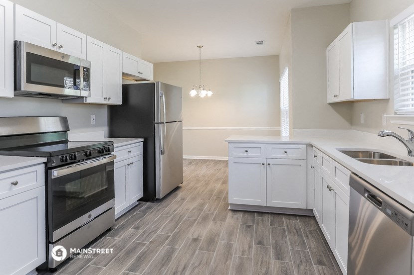 an empty kitchen with white cabinets and stainless steel appliances