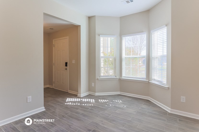 an empty room with a door and three windows