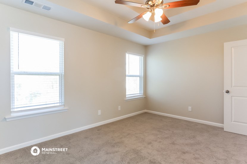 an empty room with a ceiling fan and two windows