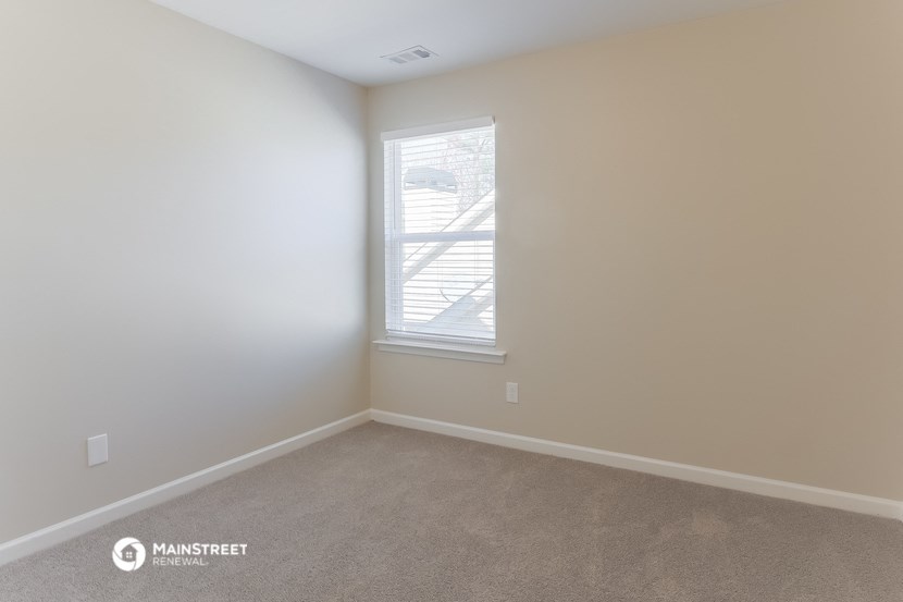 a bedroom with white walls and a window