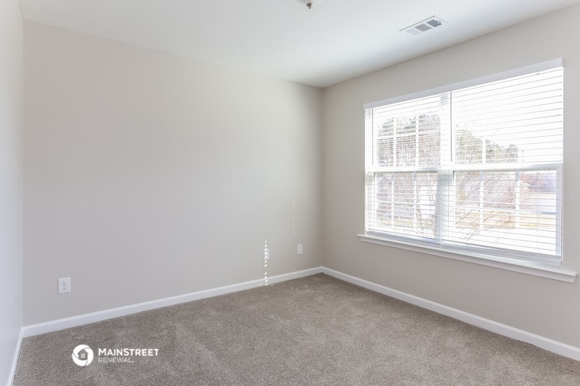 a bedroom with a large window and carpeting