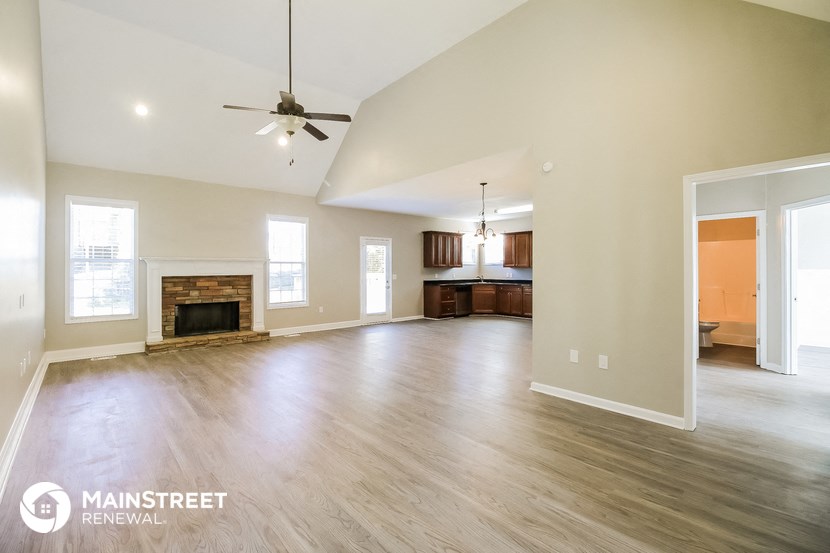 an empty living room with a fireplace and a ceiling fan