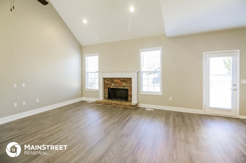 the living room with wood floors and a fireplace