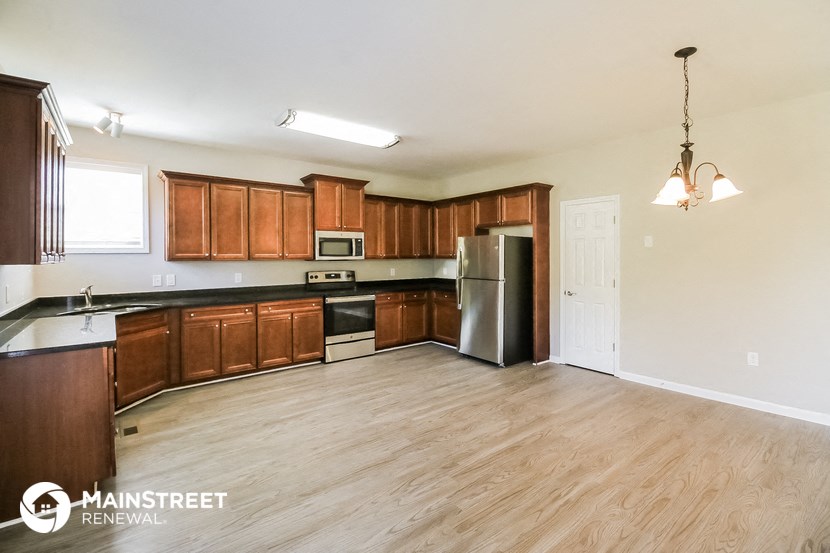 an empty kitchen with wood flooring and wooden cabinets