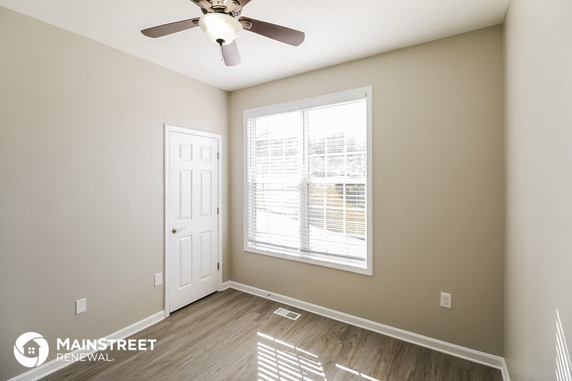 the living room of an apartment with a ceiling fan and a window