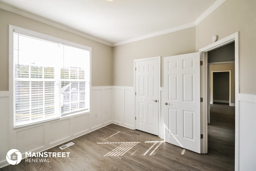 the living room of a home with white doors and a window