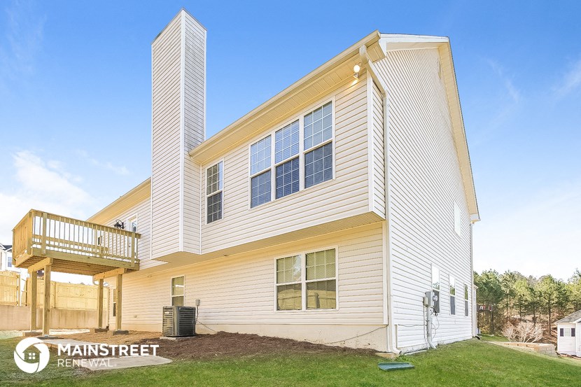 the outside of a white house with a deck and a yard
