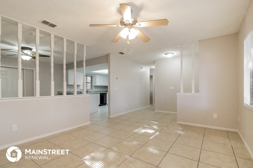 an empty living room with a ceiling fan and a tiled floor
