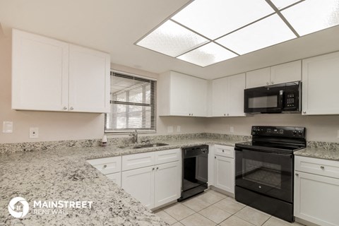 a white kitchen with black appliances and granite counter tops