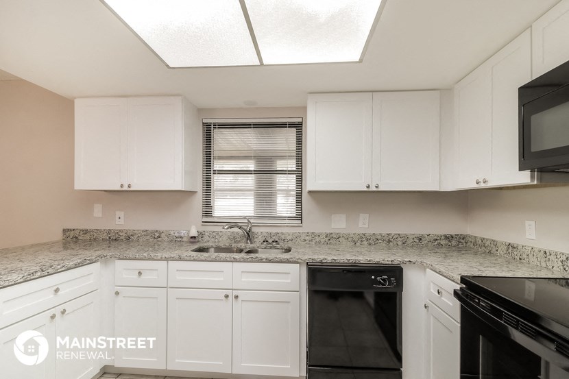 a kitchen with white cabinets and black appliances and granite counter tops