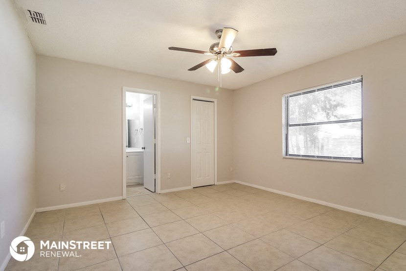 an empty living room with a ceiling fan and tiled floors