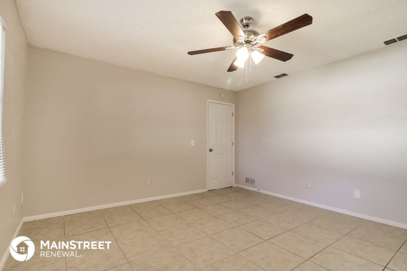 the spacious living room with ceiling fan and tile flooring