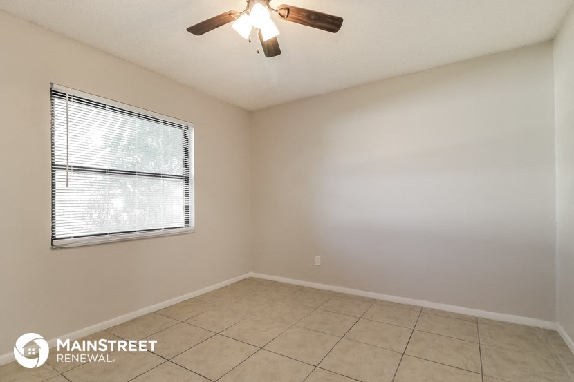 the living room of a home with a large window and a ceiling fan