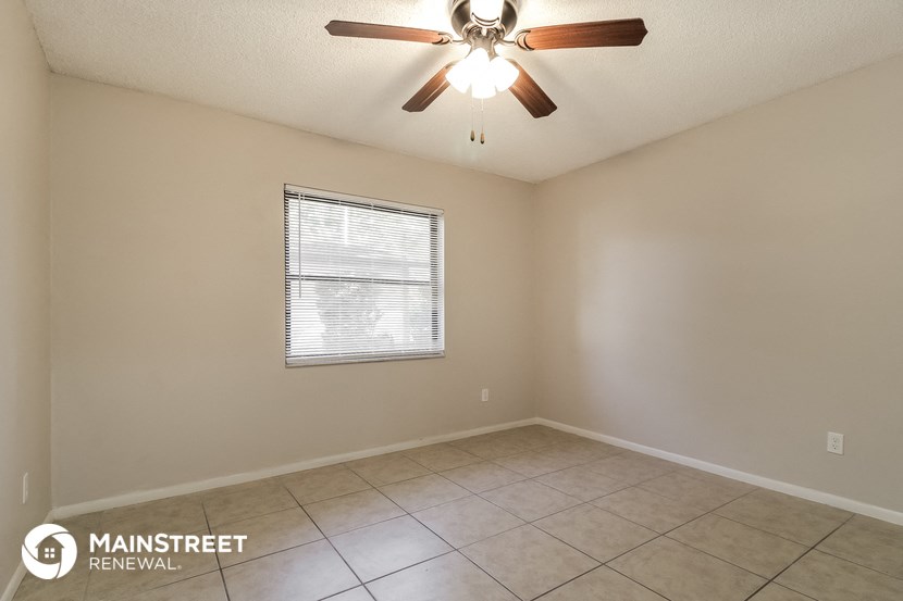 the spacious living room with a ceiling fan and tiled floor