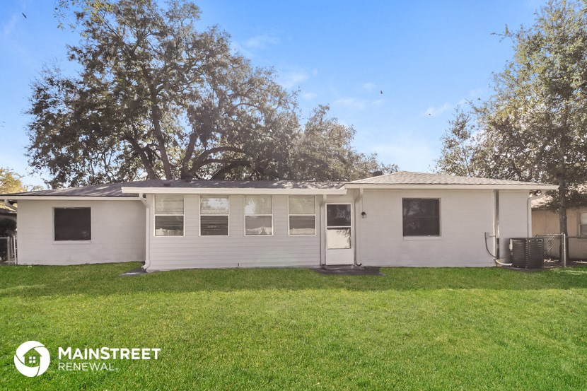 a small white house with a yard and some trees