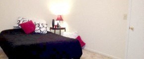 A bed with a blue cover and red pillow is in a room.