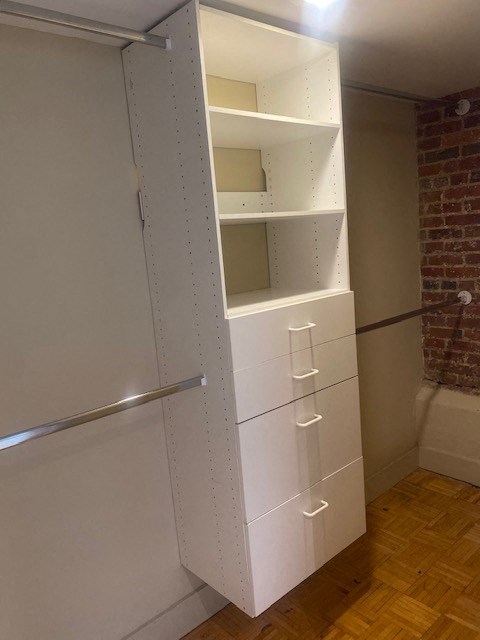 a white closet with drawers and shelves next to a toilet