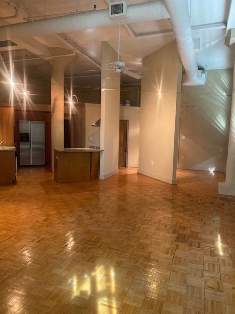 a large empty room with a wood floor and pillars